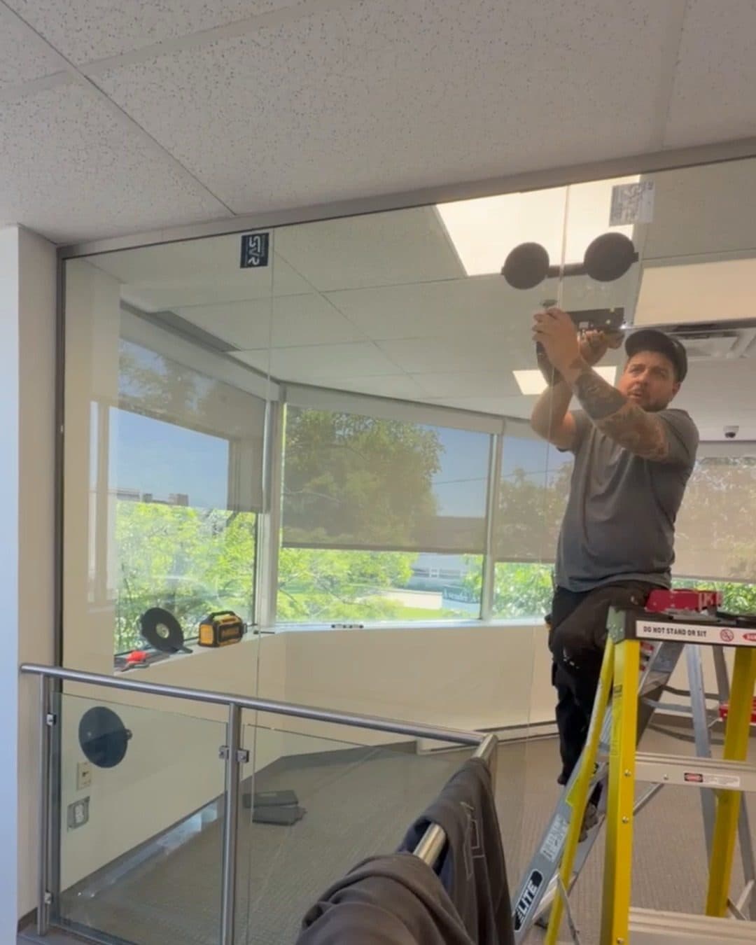 Installateur sur un escabeau qui fixe un panneau de verre